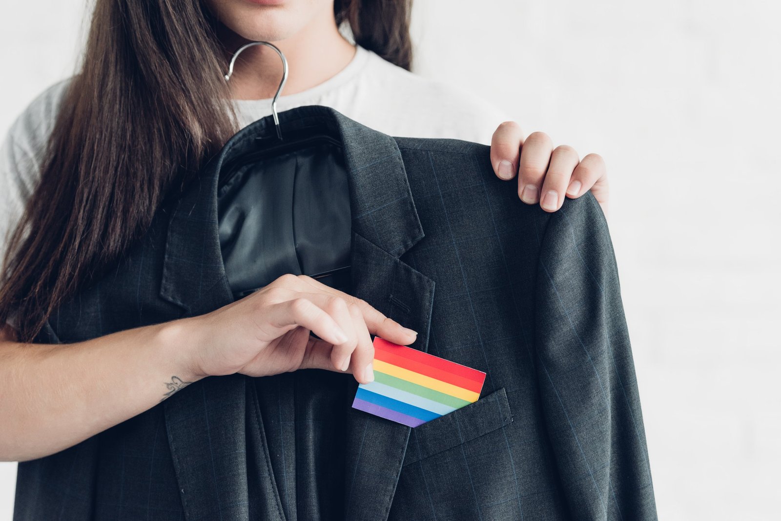 cropped shot of transgender woman taking card with pride flag out of business suit pocket